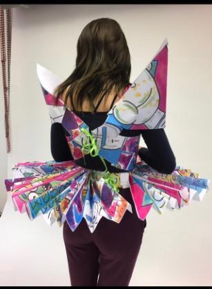 A student wearing a colorful decorated dress made from paper